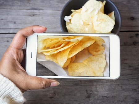 Taking a photo of potato chip with smart phoneの写真素材