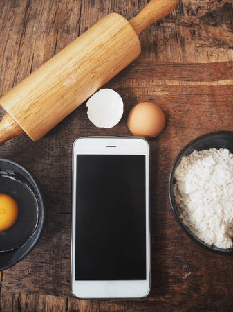 Baking ingredients with eggs and flour and smart phone