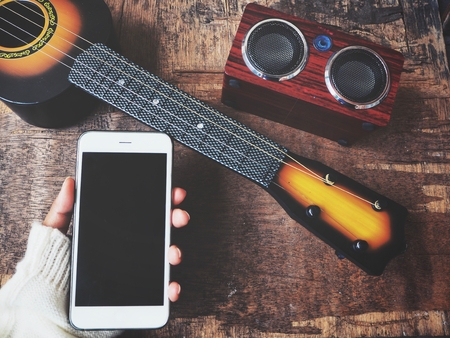 Woman using smart phone and wireless speaker with ukuleleの写真素材