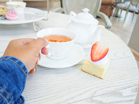 Woman eating strawberry cheesecake with english teaの写真素材