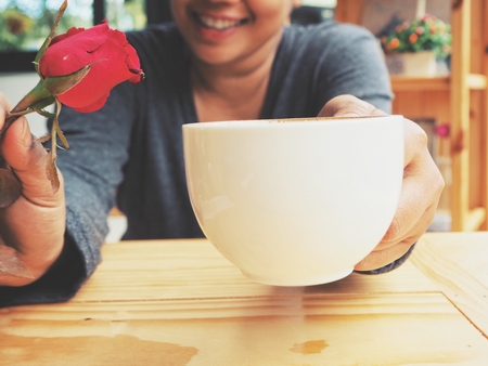 Woman drinking coffee cup and red rose in valentines dayの写真素材