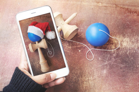 Taking a photo of kendama and christmas hat with smart phoneの写真素材