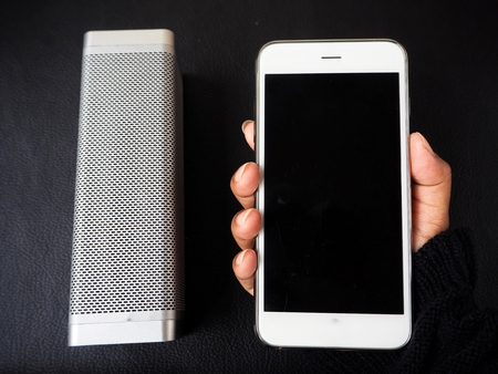 Woman using wireless speaker with smart phoneの写真素材