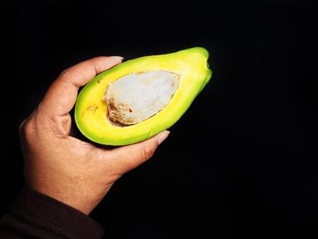 Avocado with hand on black backgroundの写真素材