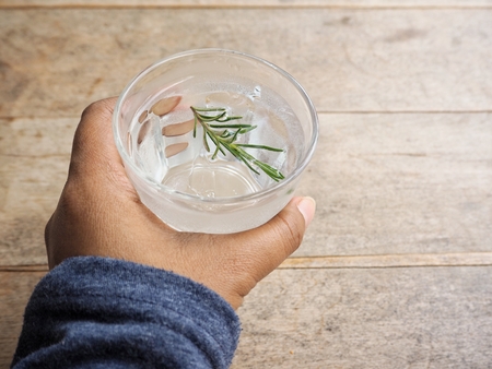 Detox drink of water with rosemary on handの写真素材