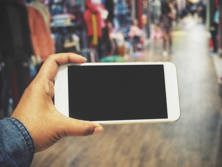 Smart phone on hand at shopping mallの写真素材