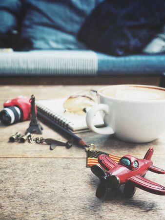 Travel accessories of toy airplane and smart phone with blank notepad and coffee cupの写真素材