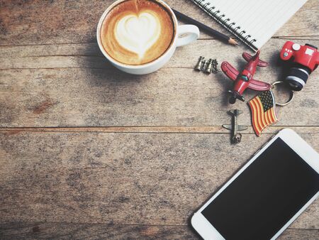 Travel accessories of smart phone with blank notepad and coffee cup with toy planeの写真素材
