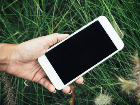 Smart phone on hand with grass flowers