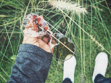 Sun glasses on hand with grass flowers