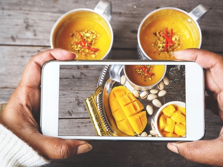 Taking a photo of  mango lassi with smart phoneの写真素材