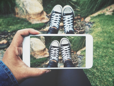 Taking a photo of sneakers with smart phoneの写真素材