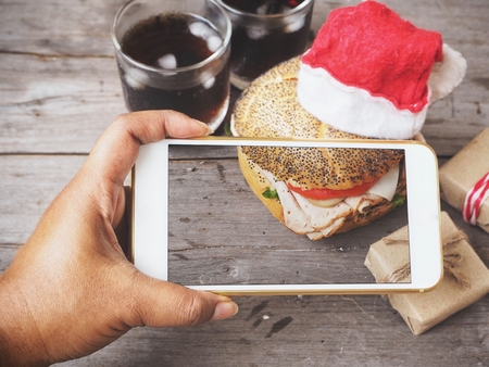 Taking a photo of hamburger and christmas decoration with smart phoneの写真素材