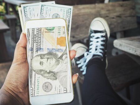 Taking a photo of dollars with smart phoneの写真素材