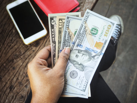 Selfie of dollars on hand with smart phone and shoes
