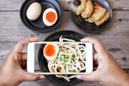 Taking a photo of udon noodle Japanese food with smart phoneの写真素材