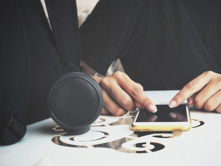 Woman using smart phone with bluetooth speaker