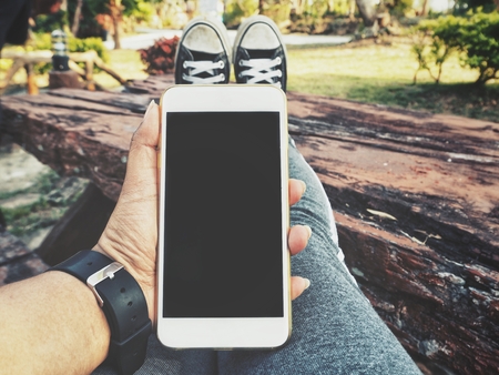 Smart phone on hand with sneakersの写真素材