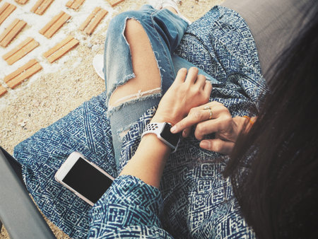 Woman playing smartwatch on hand with smart phone