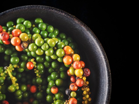 Green and red peppercorns on black backgroundの写真素材