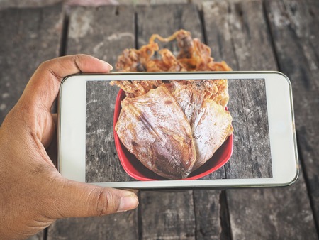 Taking a photo of dried squid with smart phones on handの写真素材
