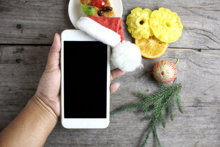 Smart phone with christmas hat and fruits cakeの写真素材