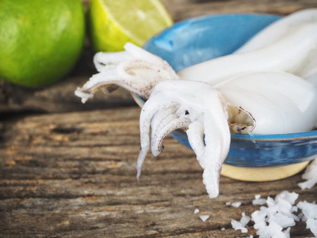 Fresh squid seafood and lime on wood background