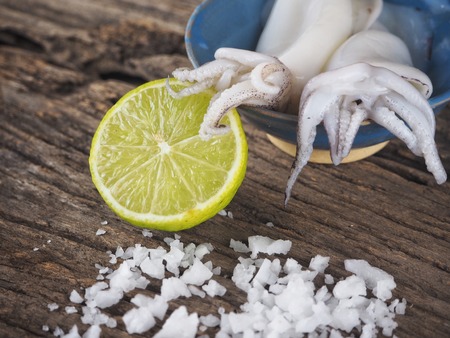 Fresh squid seafood and lime on wood backgroundの写真素材