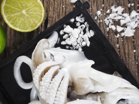Fresh squid seafood and lime on wood backgroundの写真素材