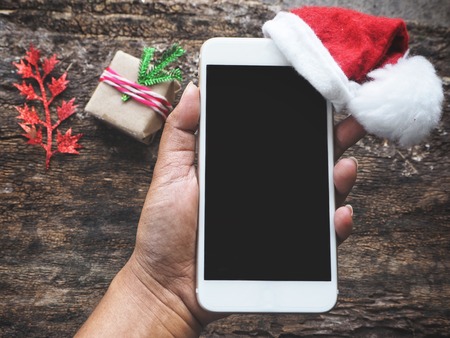 Smart phone with christmas hat on handの写真素材