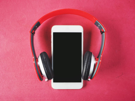 Headphones and smartphone on pink background