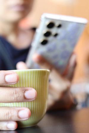 Woman using smart phone on hand and drink coffee cupの写真素材