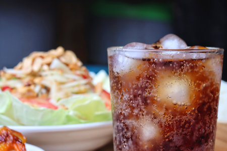 Cola soft drink with ice cubes and papaya salad spicy Thai foodの写真素材