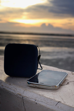 Blue bluetooth speaker and smartphone on beachの写真素材