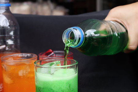 Pouring  soft drink and ice in glass