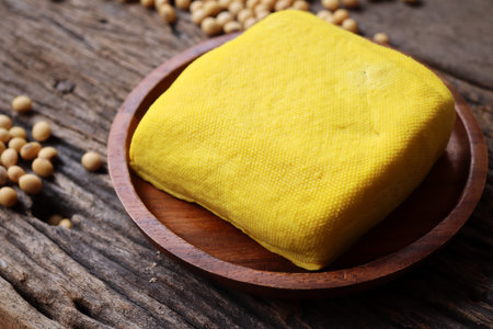 Soybeans and yellow tofu on wood background