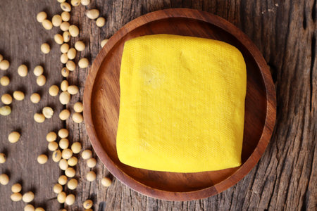 Soybeans and yellow tofu on wood background
