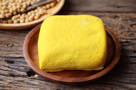 Soybeans and yellow tofu on wood background