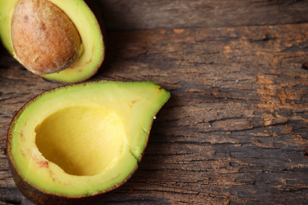 Fresh avocado halves on wooden background