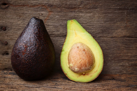 Fresh avocado halves on wooden background