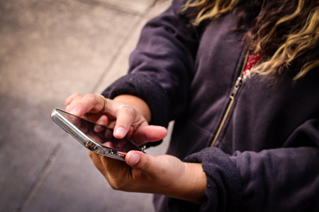 Woman using smartphone outdoors in casual jacketの写真素材