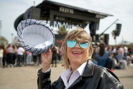A woman with sunglasses and hat in front of a stage