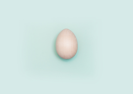 Happy Easter concept. Flat lay. Minimal concept. Top view. Wooden egg on turquoise backgroundの写真素材