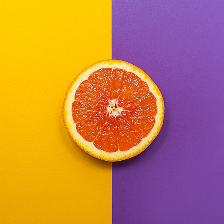Minimal style, creative layout orange and grapefruit. Flat lay. Food concept. Half an orange on yellow purple backgroundの写真素材
