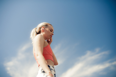 Fitness Woman Listening Music in Wireless Headphones. Beautiful Athletic Fit Girl In Bright Sports Clothing Relaxing After Training. Sport style Bluetooth earphonesの写真素材