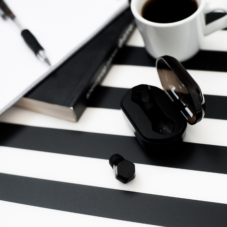 Stylish minimalistic workspace with smartphone mock up, book, notebook, pencil, cup of coffee, bakery, wireless earphones isolated on striped black and white background. Flat lay style Top viewの写真素材