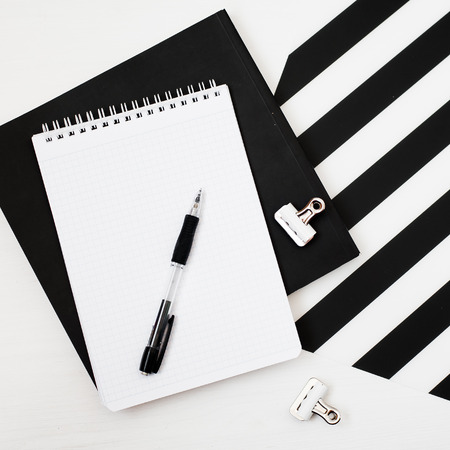 Stylish minimalistic workspace with smartphone mock up, book, notebook, pencil, cup of coffee, bakery, wireless earphones isolated on striped black and white background. Flat lay style Top viewの写真素材