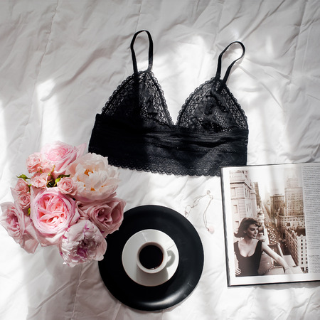 Flat lay, magazines, social media. Top view black lace lingerie. Beauty blog concept. Woman fashion accessories, underwear, bouquet of roses and pions, coffee on white bed background.の写真素材