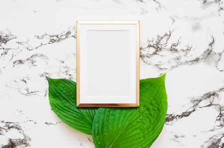 Gold photo frame with tropical leaves on marble background. Mock up frame with copyspace. Flat lay,...