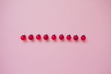 Creative christmas flat lay composition with red glass balls on pink background. Top view